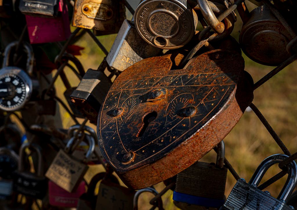 Detailed shot of a rusty heart-shaped padlock among other locks, symbolizing enduring love.