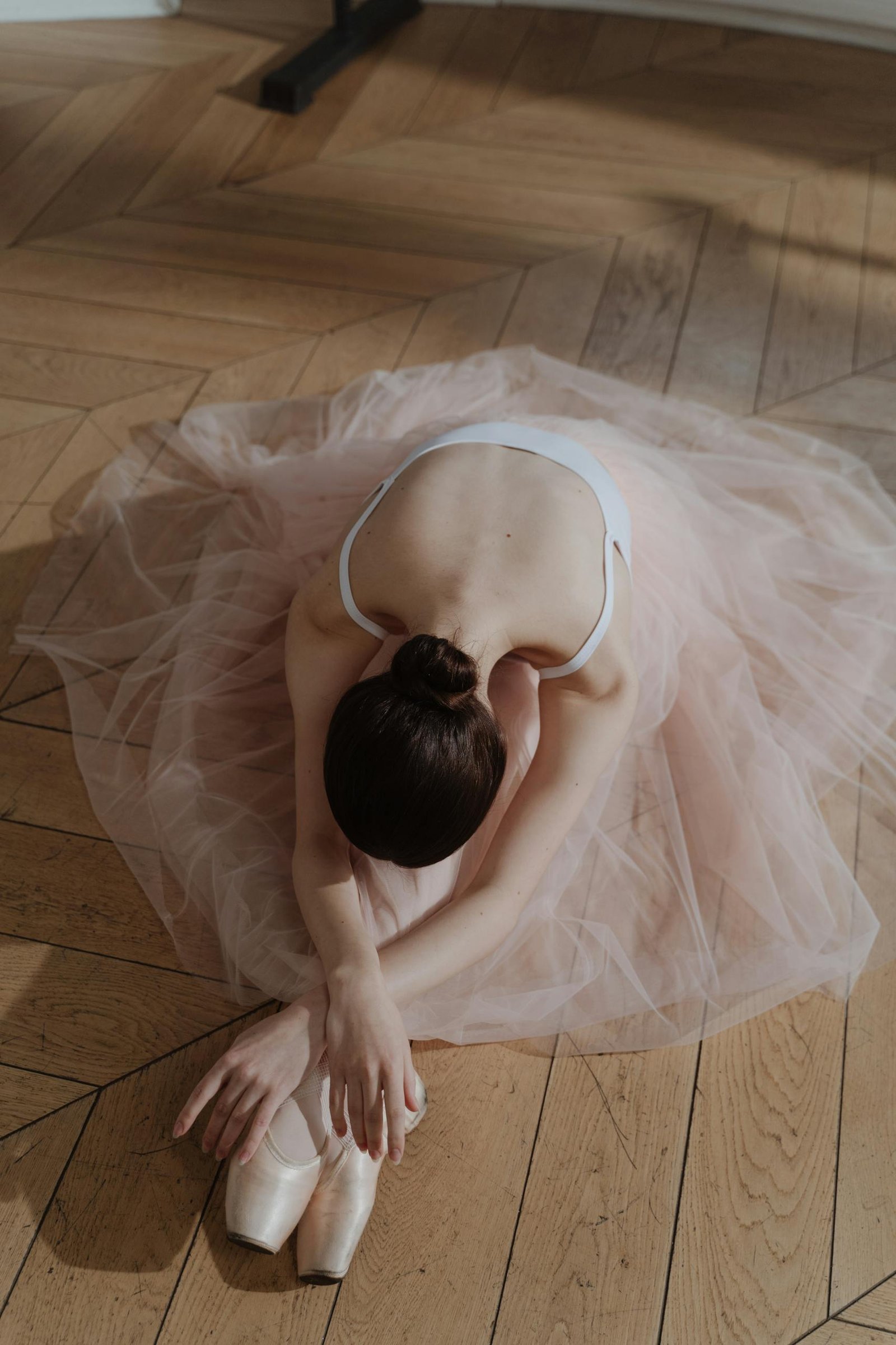 Ballerina in a pink tulle skirt poses gracefully indoors, showcasing elegance and poise.