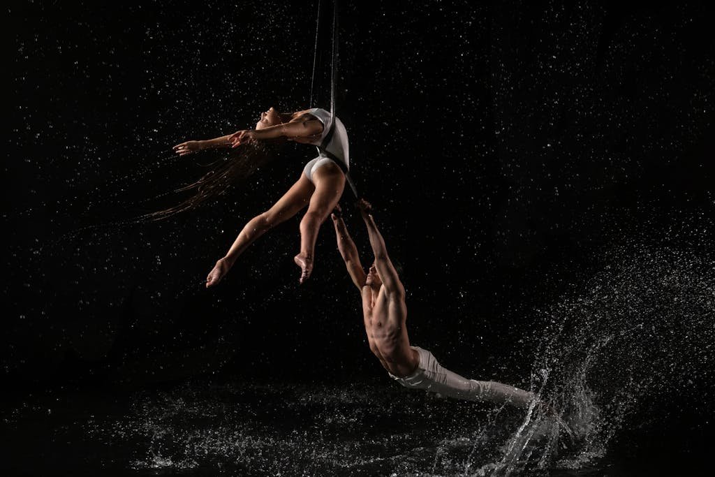 Captivating aerial dance with dynamic water splashes against a dark background.