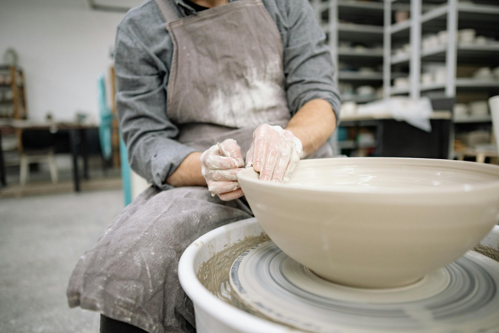 Close-up of a skilled artisan shaping clay on a pottery wheel in a workshop.