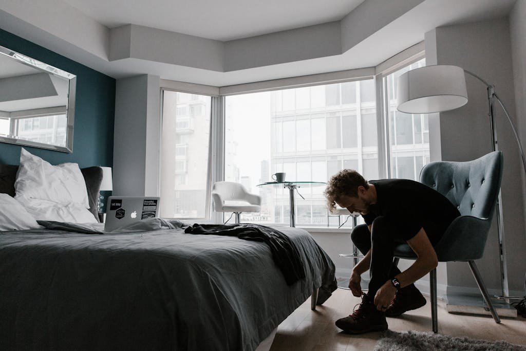 Contemporary hotel room with a man tying shoes in a bright Toronto setting.