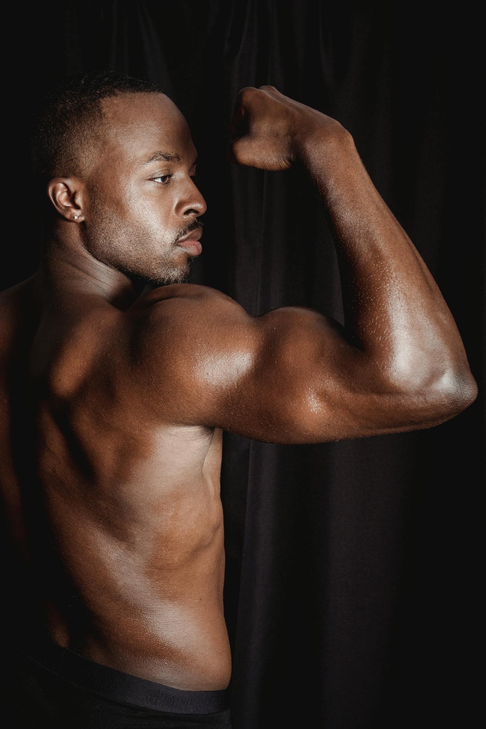 Powerful pose of a shirtless African American man flexing his bicep.
