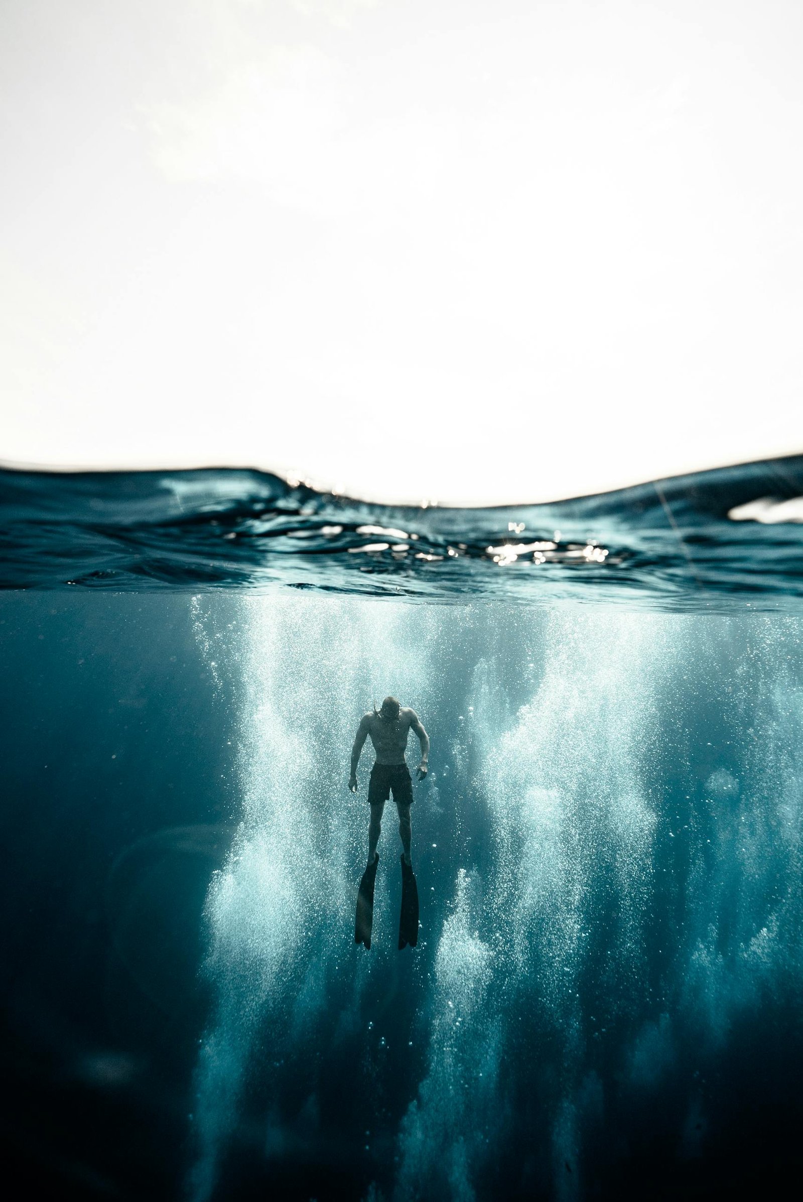 Silhouette of a diver swimming underwater in the ocean off Bali, Indonesia.