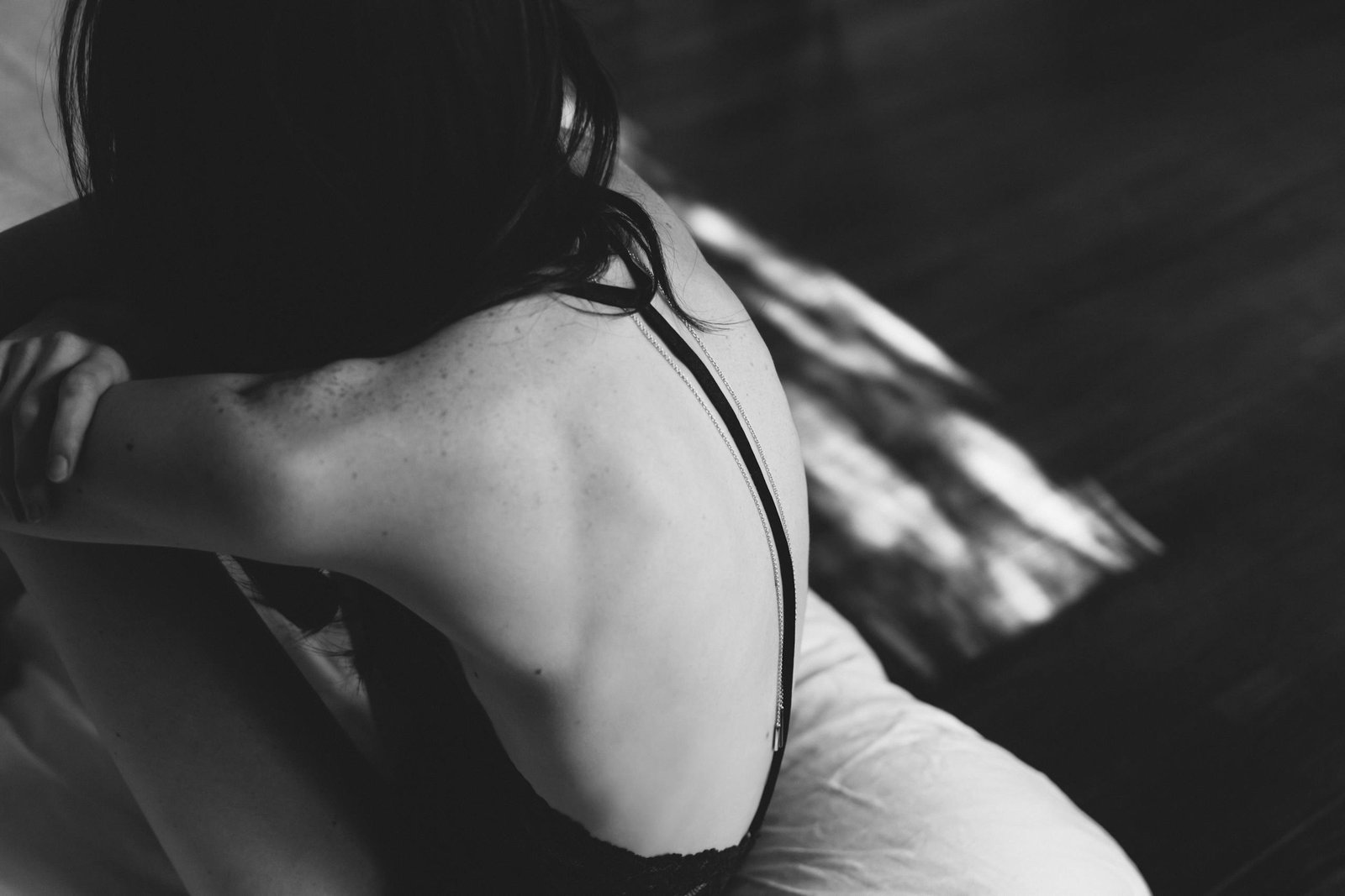 An artistic black and white portrait of a woman from behind, emphasizing form and texture.