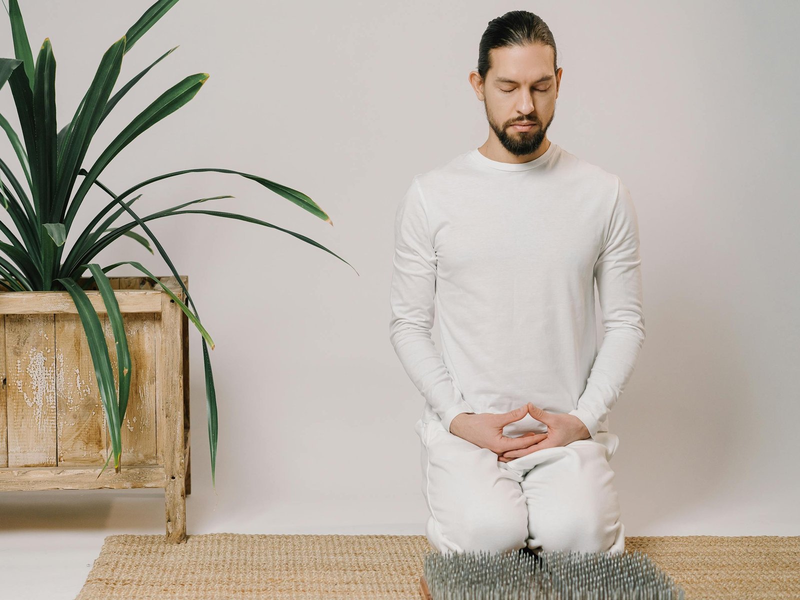 A man meditates indoors in a minimalist setting, focusing on relaxation and mindfulness.